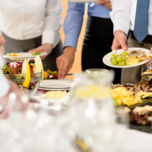 Image is of a buffet table with a bunch of people filling their plates.