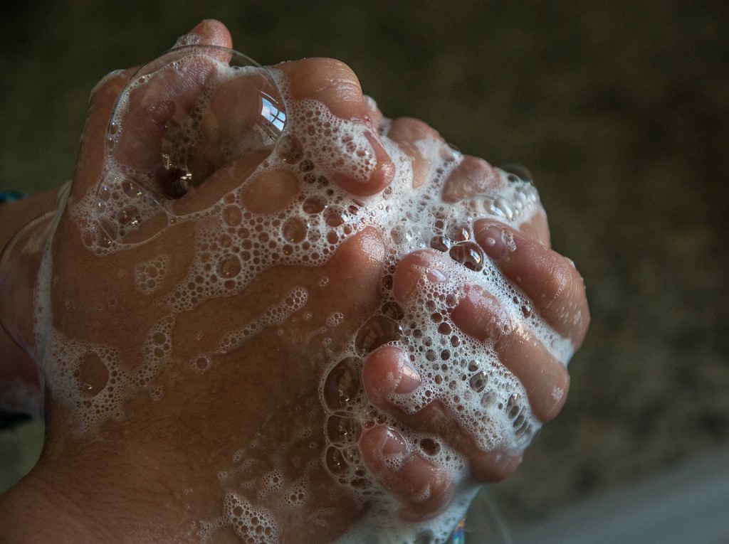 Image shows a close up of a pair of hands being washing with soap suds all over them.